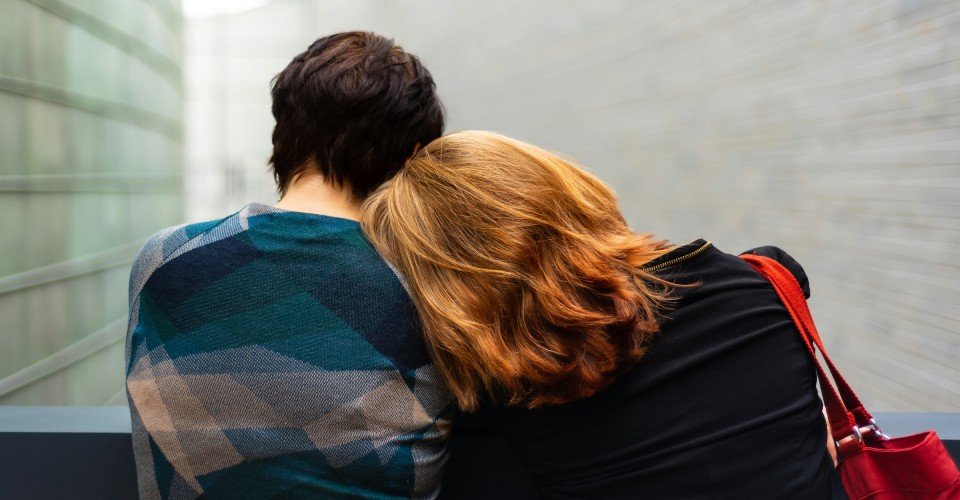 Two people sat down supporting each other through grief